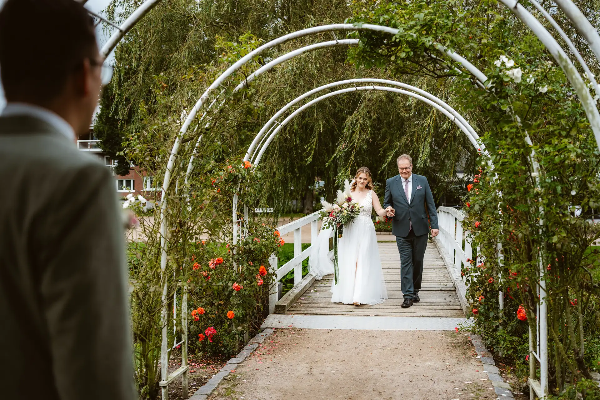 Rosarium Uetersen, Braut geht mit Brautvater über die weißen Brücke zur Hochzeitsinsel.